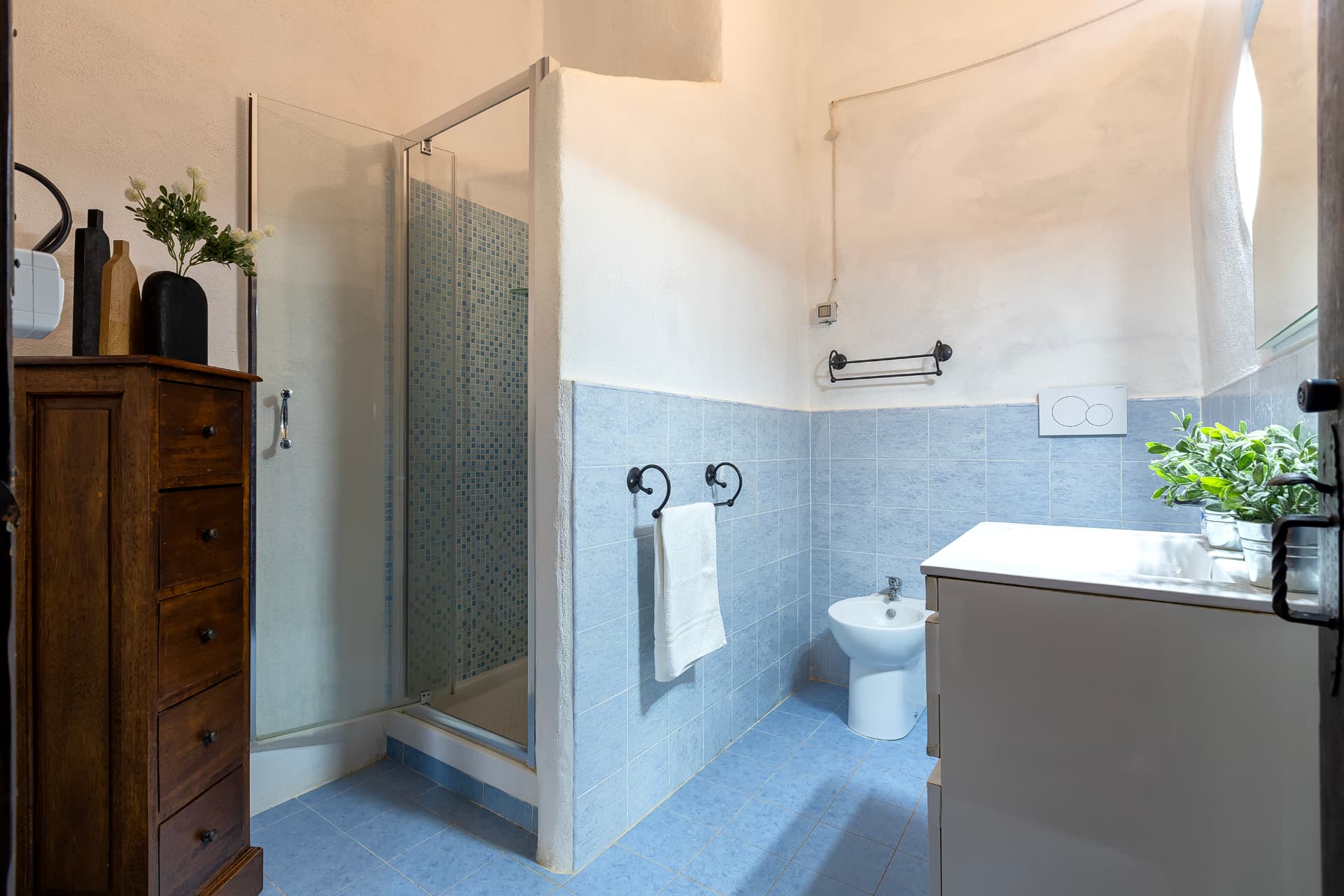 Bagno con doccia in mosaico e mobile in legno