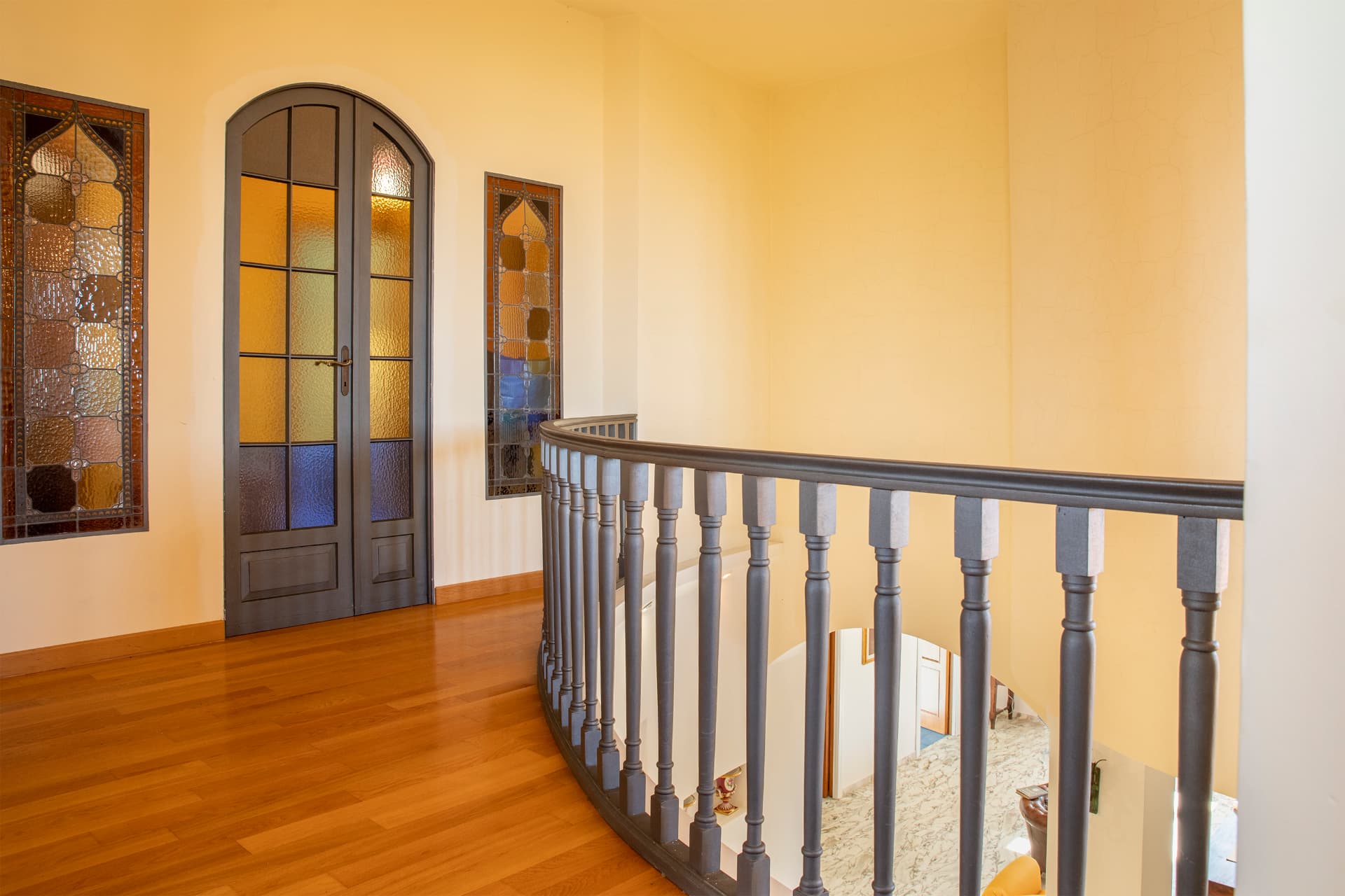 Il pianerottolo con porta e vetrate decorate al livello superiore