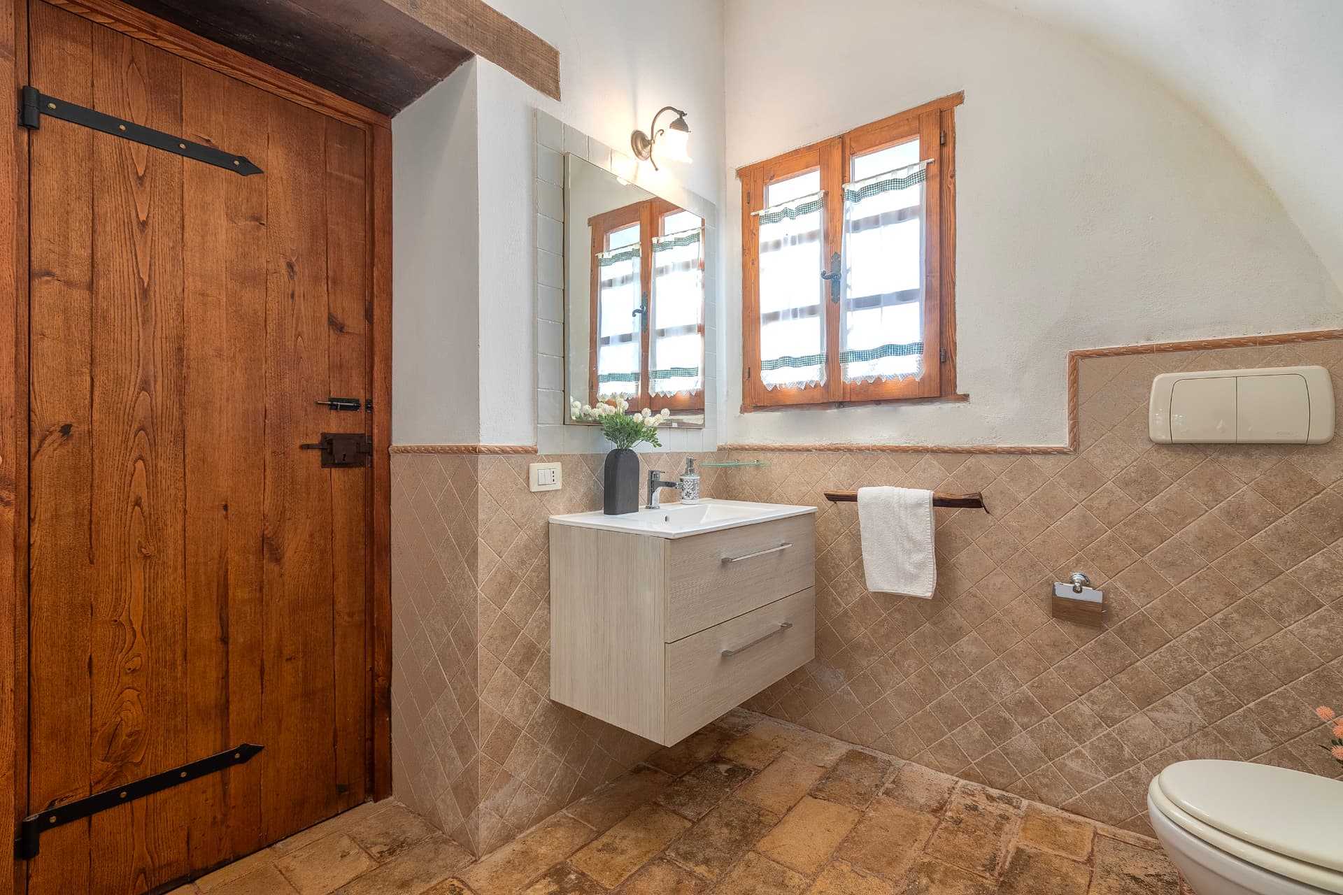 Bagno con porta in legno e piastrelle in cotto